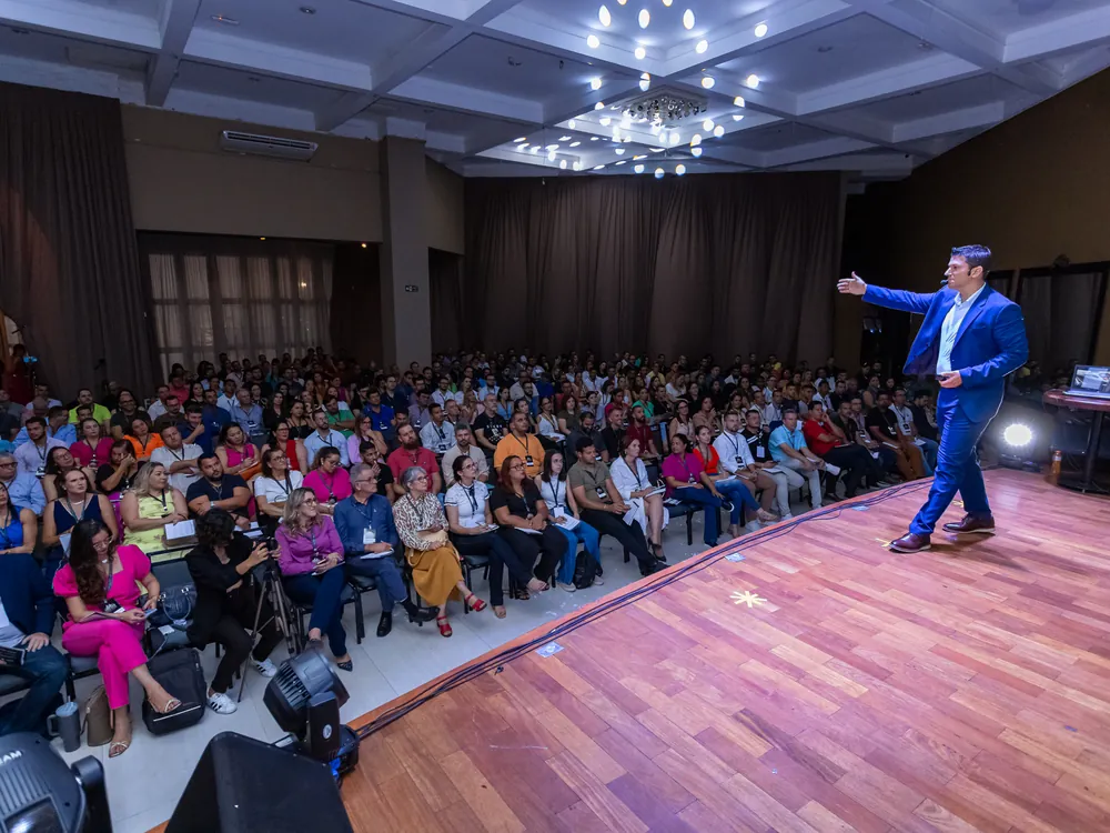 Roberto Tostes no palco diante de auditório lotado